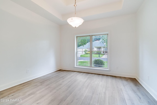 unfurnished room featuring light wood-type flooring and a tray ceiling