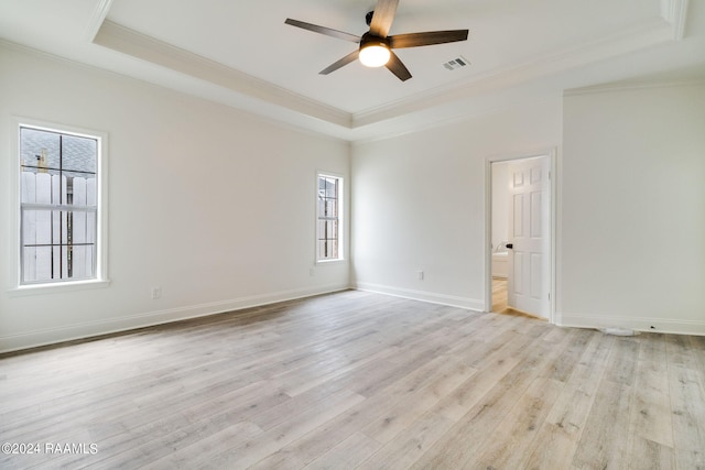 empty room featuring ceiling fan, a raised ceiling, light hardwood / wood-style flooring, and ornamental molding