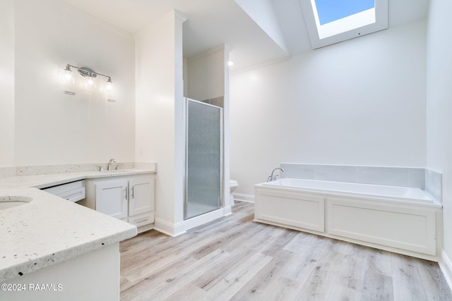 full bathroom with independent shower and bath, hardwood / wood-style flooring, a skylight, vanity, and toilet