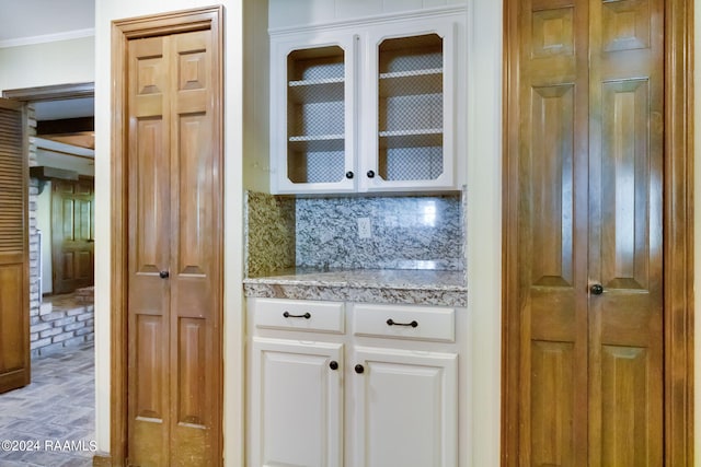 kitchen with white cabinetry, ornamental molding, and tasteful backsplash