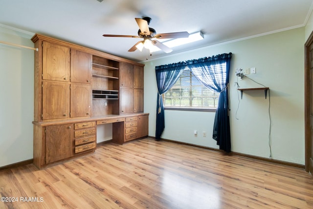 unfurnished office featuring ceiling fan, built in desk, crown molding, and light wood-type flooring