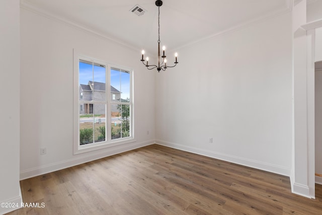 unfurnished room with wood-type flooring, a notable chandelier, and ornamental molding