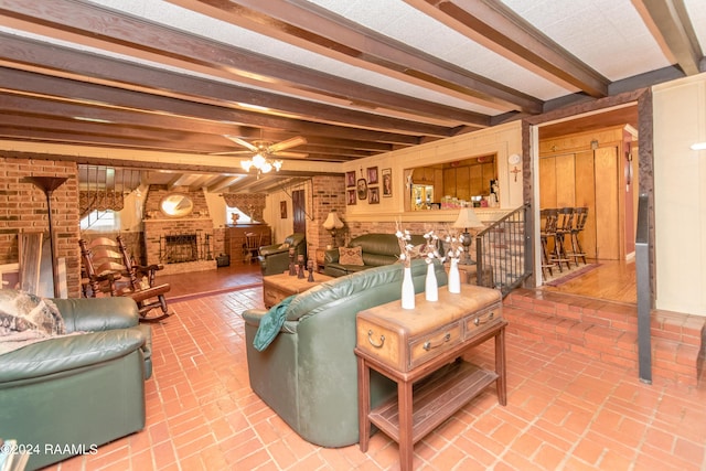 living room featuring wooden walls, a brick fireplace, ceiling fan, beamed ceiling, and brick wall