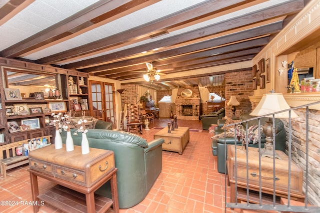 living room featuring ceiling fan, beamed ceiling, brick wall, and a brick fireplace