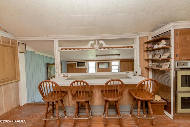 dining area featuring light hardwood / wood-style floors, crown molding, and wooden walls