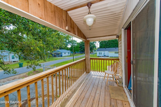 wooden terrace featuring covered porch and a lawn