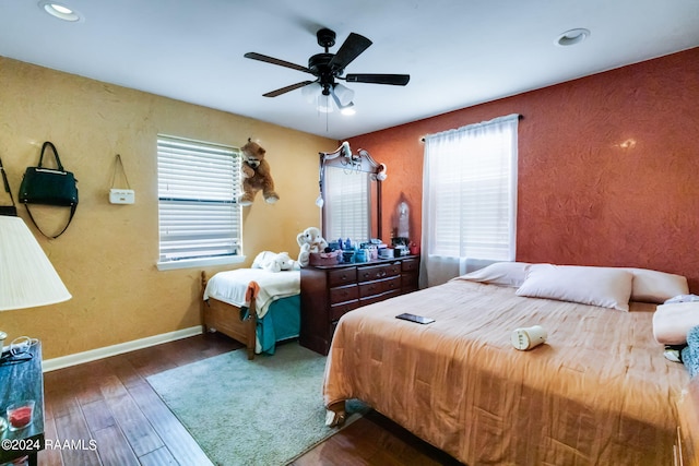 bedroom featuring ceiling fan, dark hardwood / wood-style floors, and multiple windows