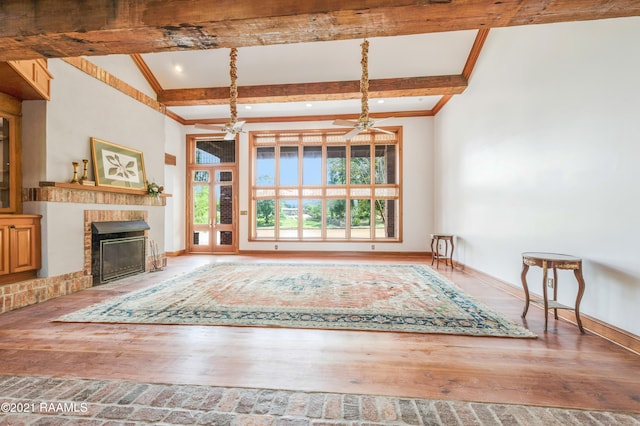 unfurnished living room with ceiling fan, vaulted ceiling with beams, and wood-type flooring