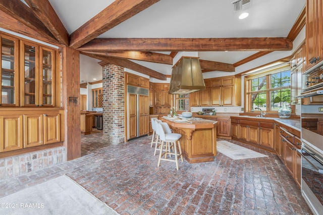 kitchen with island range hood, brick wall, a center island, sink, and a breakfast bar