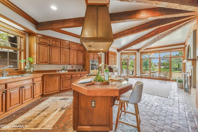 kitchen with double oven, a kitchen breakfast bar, a center island, sink, and lofted ceiling with beams