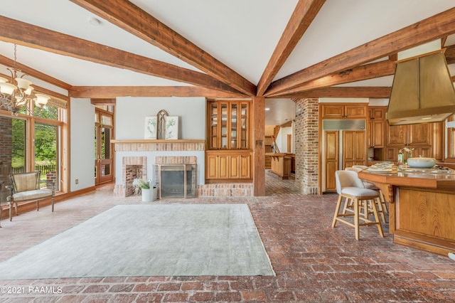 unfurnished living room featuring vaulted ceiling with beams, brick wall, an inviting chandelier, and a fireplace