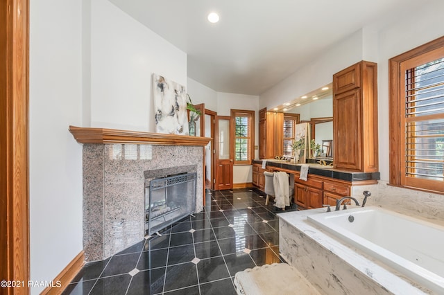 bathroom with tiled bath, tile flooring, vanity, and a tile fireplace