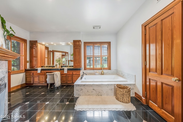 bathroom featuring tile floors, plenty of natural light, vanity, and tiled tub