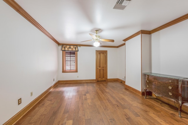 empty room featuring ceiling fan, crown molding, and hardwood / wood-style flooring