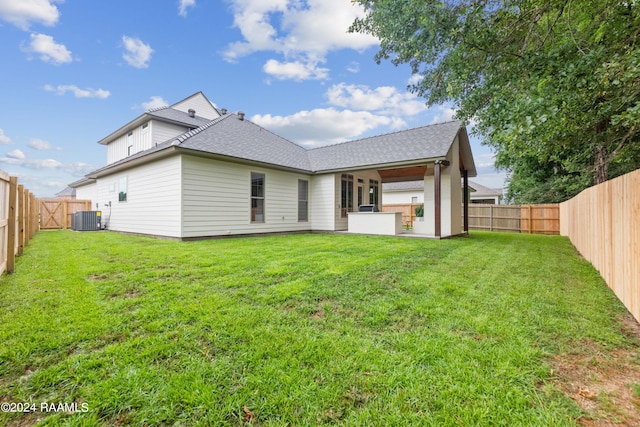 rear view of house with a lawn and central AC unit