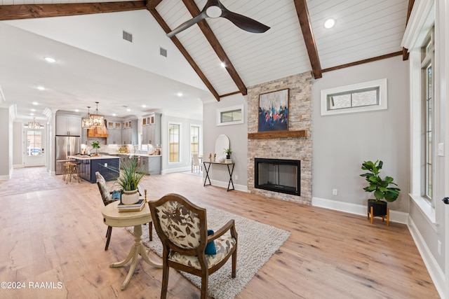 living room with a healthy amount of sunlight, a stone fireplace, and light hardwood / wood-style flooring