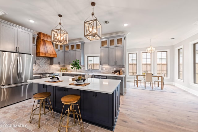 kitchen with stainless steel fridge, gray cabinetry, custom range hood, pendant lighting, and a kitchen island