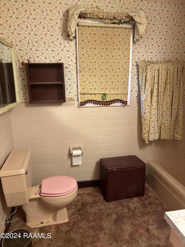 bathroom featuring a tub to relax in, tile walls, and toilet