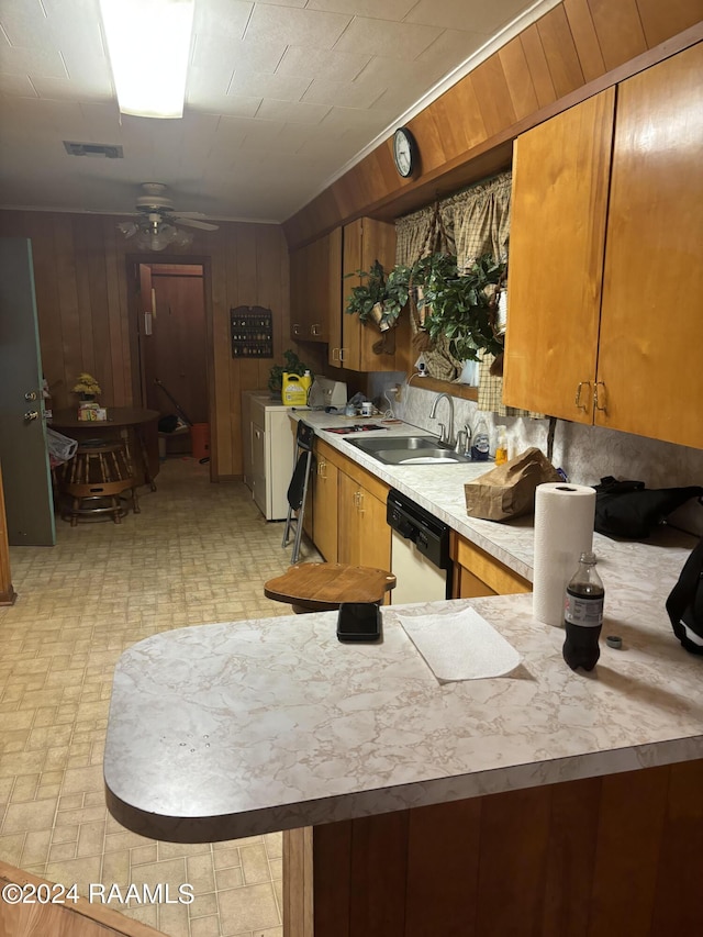 kitchen with ceiling fan, sink, separate washer and dryer, white dishwasher, and wooden walls