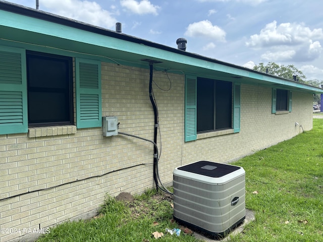 view of side of property with central AC unit and a lawn