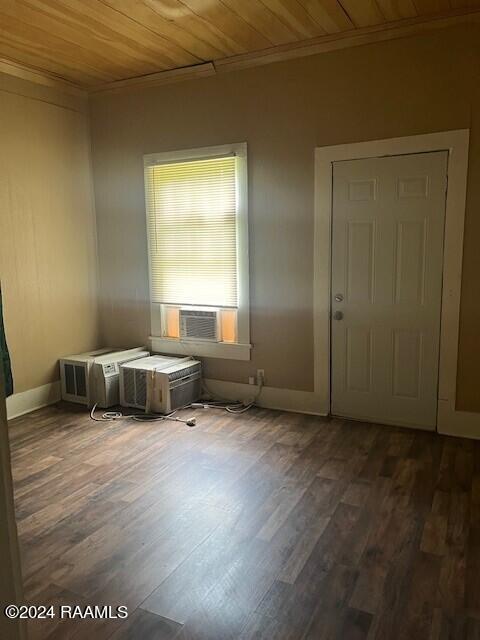 empty room featuring crown molding, dark wood-type flooring, cooling unit, and wooden ceiling