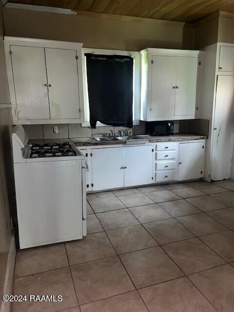 kitchen featuring sink, wooden ceiling, white cabinets, white gas stove, and light tile patterned flooring