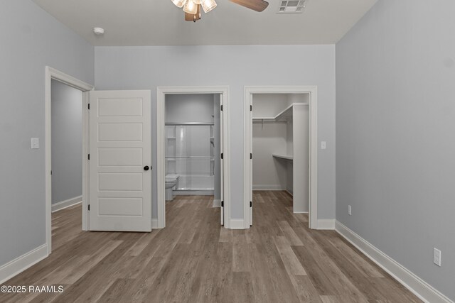 210 E D St, Rayne, LA 70578 - unfurnished bedroom featuring wood finished floors, a closet, a spacious closet, baseboards, and visible vents