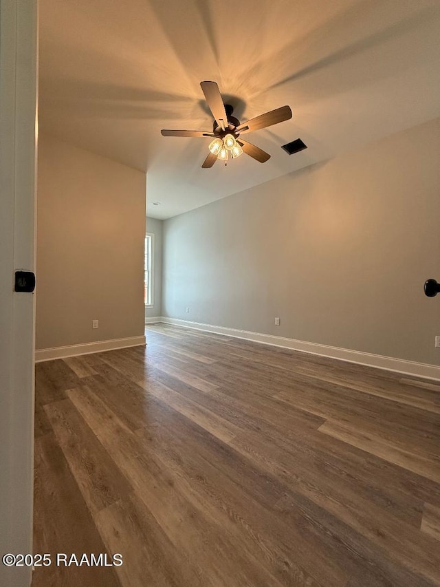 unfurnished room featuring a ceiling fan, dark wood finished floors, and baseboards