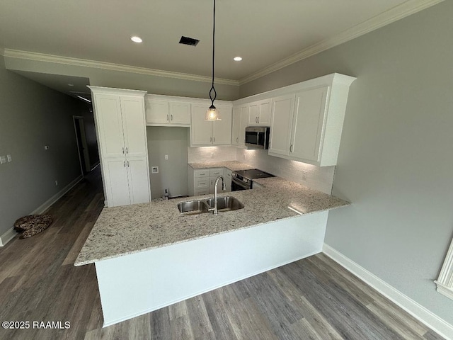 kitchen with a peninsula, appliances with stainless steel finishes, a sink, and white cabinets