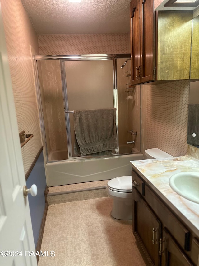 full bathroom with tile flooring, a textured ceiling, combined bath / shower with glass door, vanity, and toilet