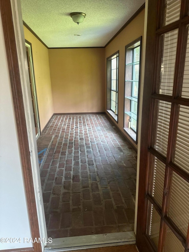 spare room featuring a textured ceiling and crown molding