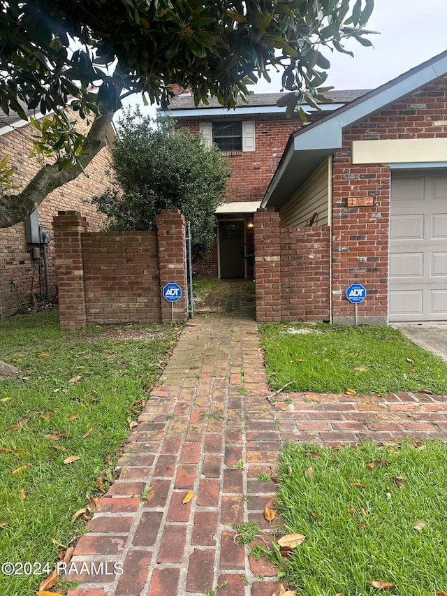 doorway to property with a garage and a lawn