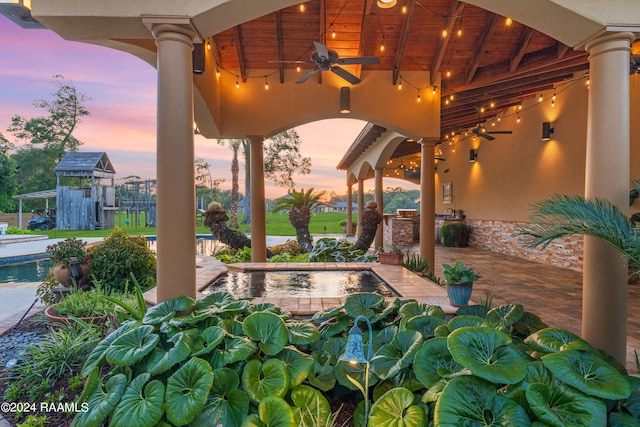 patio terrace at dusk featuring area for grilling and ceiling fan