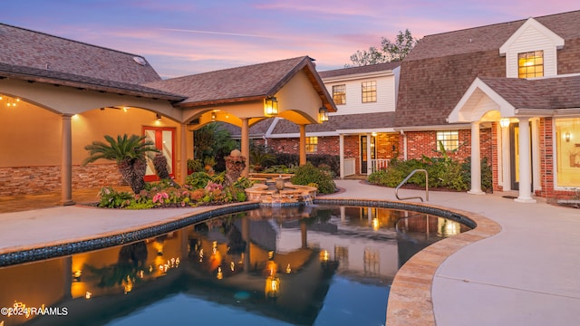 pool at dusk featuring a patio area