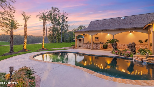 pool at dusk featuring a lawn and a patio