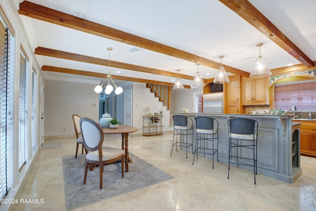 kitchen with pendant lighting, a center island, built in refrigerator, tasteful backsplash, and beam ceiling