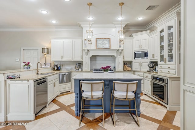 kitchen featuring hanging light fixtures, white cabinets, light stone counters, a kitchen island, and appliances with stainless steel finishes