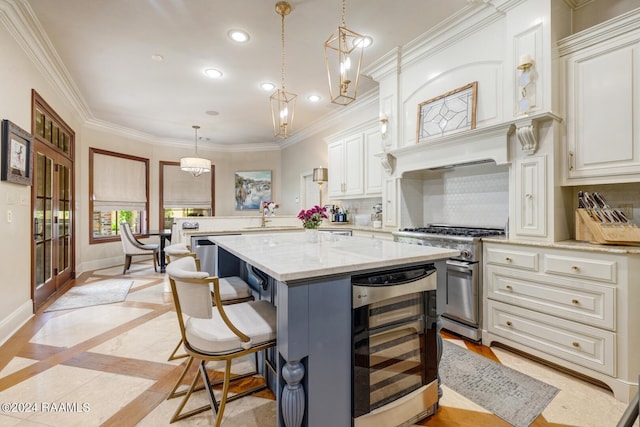 kitchen with beverage cooler, pendant lighting, high end stainless steel range, white cabinets, and a kitchen island