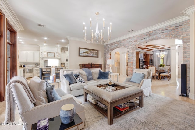 tiled living room featuring decorative columns, crown molding, and an inviting chandelier