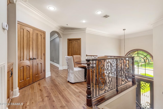 corridor with ornamental molding and light hardwood / wood-style flooring