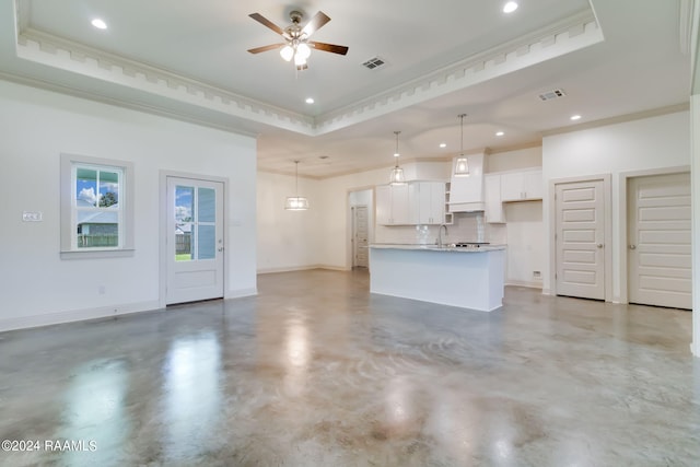 kitchen with ornamental molding, a tray ceiling, decorative light fixtures, white cabinets, and a kitchen island