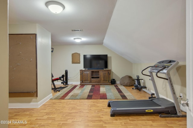 workout area with light hardwood / wood-style flooring and vaulted ceiling