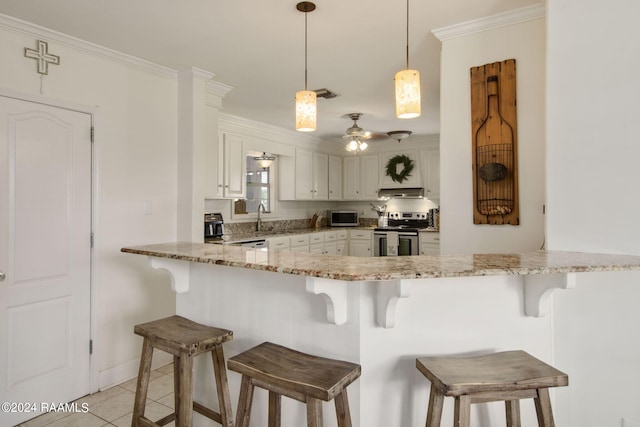 kitchen with a breakfast bar area, appliances with stainless steel finishes, light tile patterned floors, kitchen peninsula, and decorative light fixtures