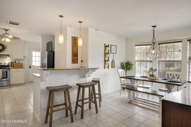 kitchen with light tile patterned floors, stainless steel refrigerator, ceiling fan, white cabinets, and stove