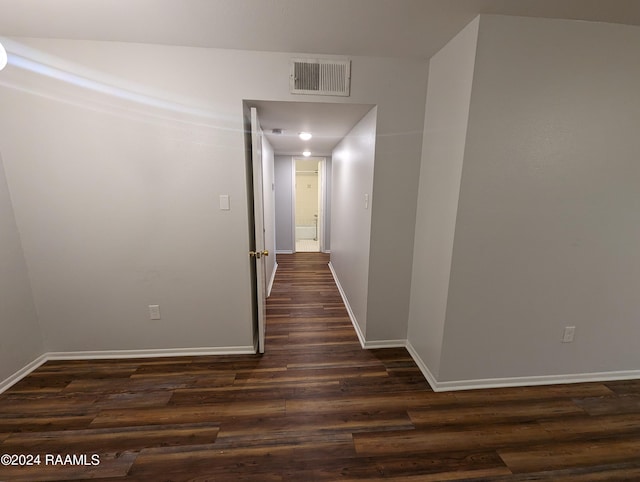 hallway with dark wood finished floors, visible vents, and baseboards