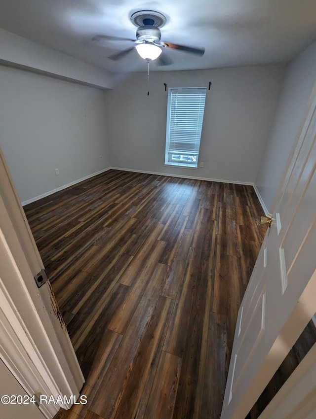 empty room with dark wood-style floors, baseboards, and a ceiling fan