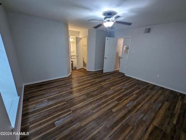 unfurnished bedroom with ensuite bathroom, a ceiling fan, visible vents, baseboards, and dark wood finished floors