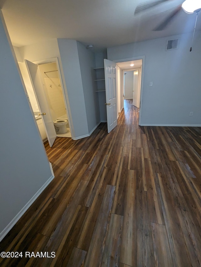 empty room featuring ceiling fan, dark wood finished floors, visible vents, and baseboards