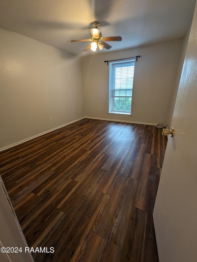 spare room featuring a ceiling fan, dark wood-style flooring, and baseboards