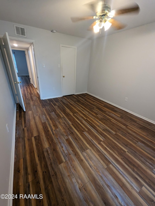 unfurnished room with ceiling fan, baseboards, visible vents, and dark wood finished floors